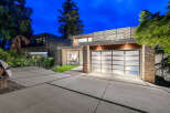 Experience modern luxury in this stunning residence featuring a sleek glass garage door and natural stone accents.