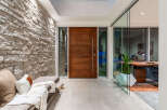 Experience modern luxury with this stunning entryway featuring a striking stone accent wall and a sleek, oversized wooden door.