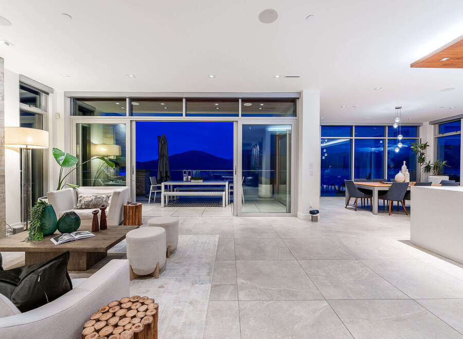 Experience luxurious modern living in this stunning open-concept home, featuring a spacious living area that seamlessly flows into a dining space and an outdoor patio.