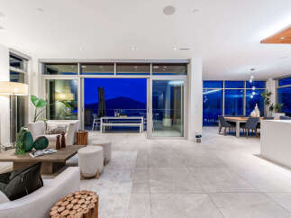 Experience luxurious modern living in this stunning open-concept home, featuring a spacious living area that seamlessly flows into a dining space and an outdoor patio.