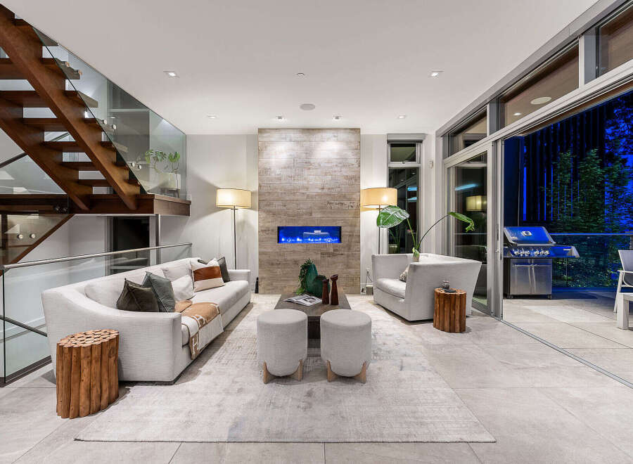 Experience modern luxury in this stunning living room, featuring a sleek fireplace with a blue flame and a striking wood-paneled accent wall.