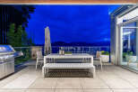 Enjoy breathtaking sunset views from this stunning outdoor living space, complete with a modern dining set and a built-in grill.