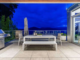 Enjoy breathtaking sunset views from this stunning outdoor living space, complete with a modern dining set and a built-in grill.