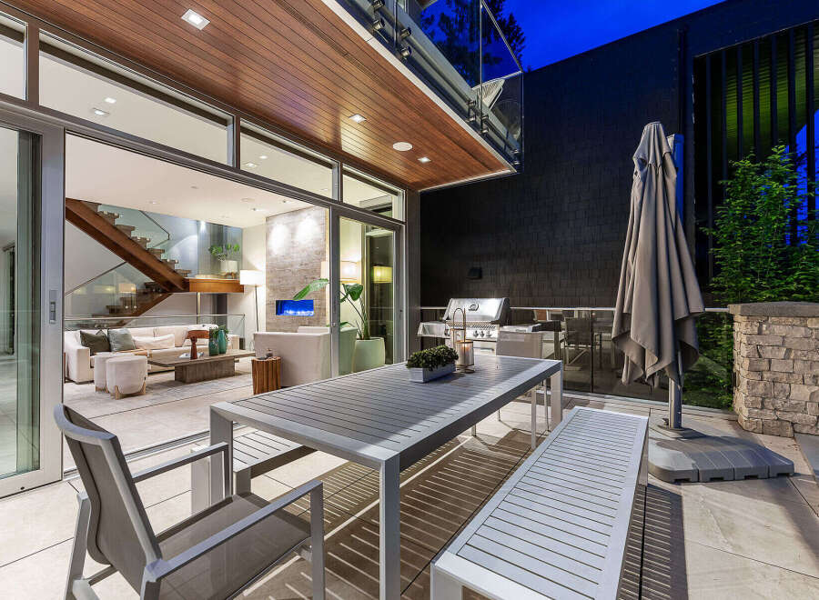Experience seamless indoor-outdoor living with this stunning patio featuring a modern dining set and a built-in grill.