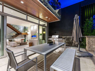 Experience seamless indoor-outdoor living with this stunning patio featuring a modern dining set and a built-in grill.