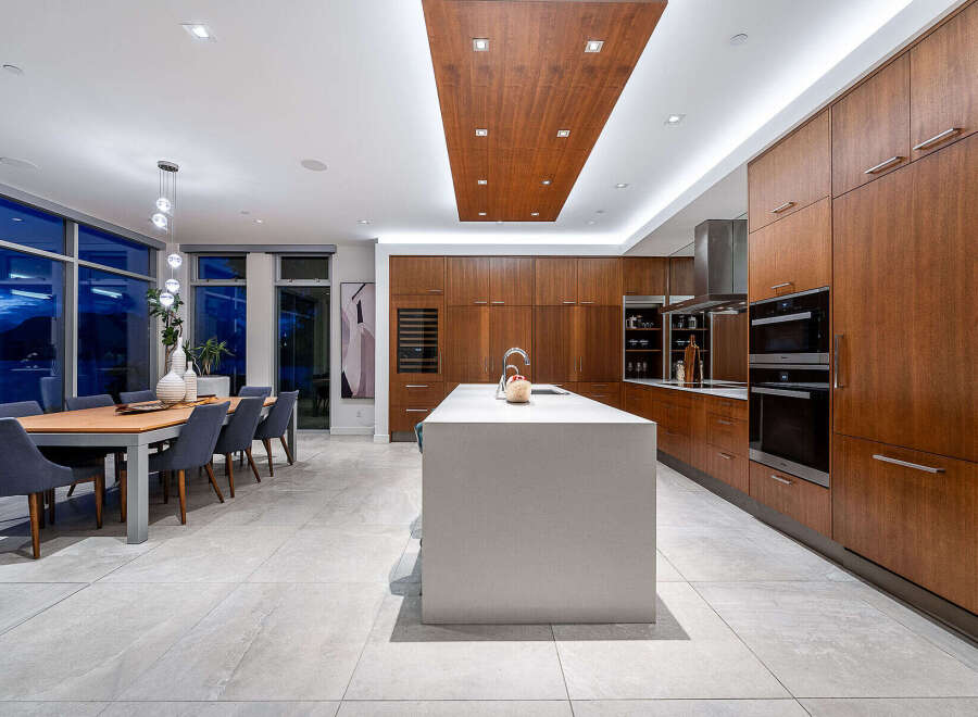 Experience luxury living in this modern kitchen and dining area, featuring sleek wood cabinetry and a spacious island perfect for entertaining.