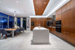 Experience luxury living in this modern kitchen and dining area, featuring sleek wood cabinetry and a spacious island perfect for entertaining.