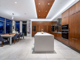 Experience luxury living in this modern kitchen and dining area, featuring sleek wood cabinetry and a spacious island perfect for entertaining.
