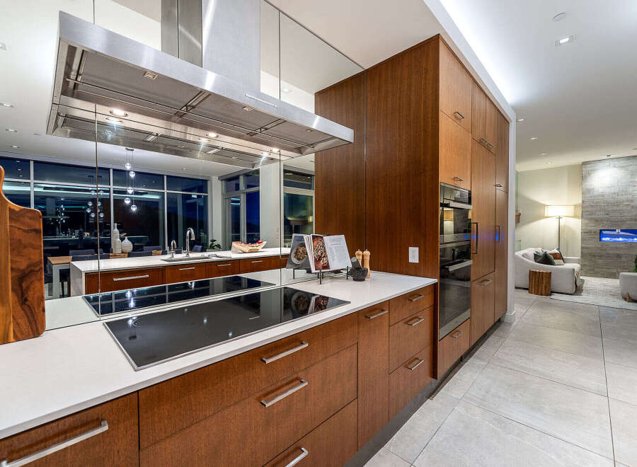 Experience modern luxury in this stunning kitchen featuring sleek, dark wood cabinetry and a spacious island with a built-in induction cooktop.