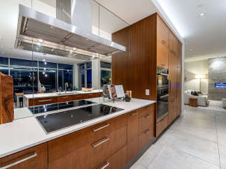 Experience modern luxury in this stunning kitchen featuring sleek, dark wood cabinetry and a spacious island with a built-in induction cooktop.