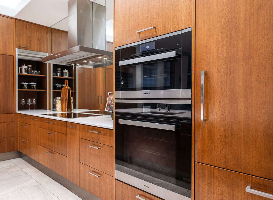 Experience modern luxury in this stunning kitchen, featuring sleek Miele appliances and rich wood cabinetry.