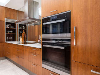 Experience modern luxury in this stunning kitchen, featuring sleek Miele appliances and rich wood cabinetry.