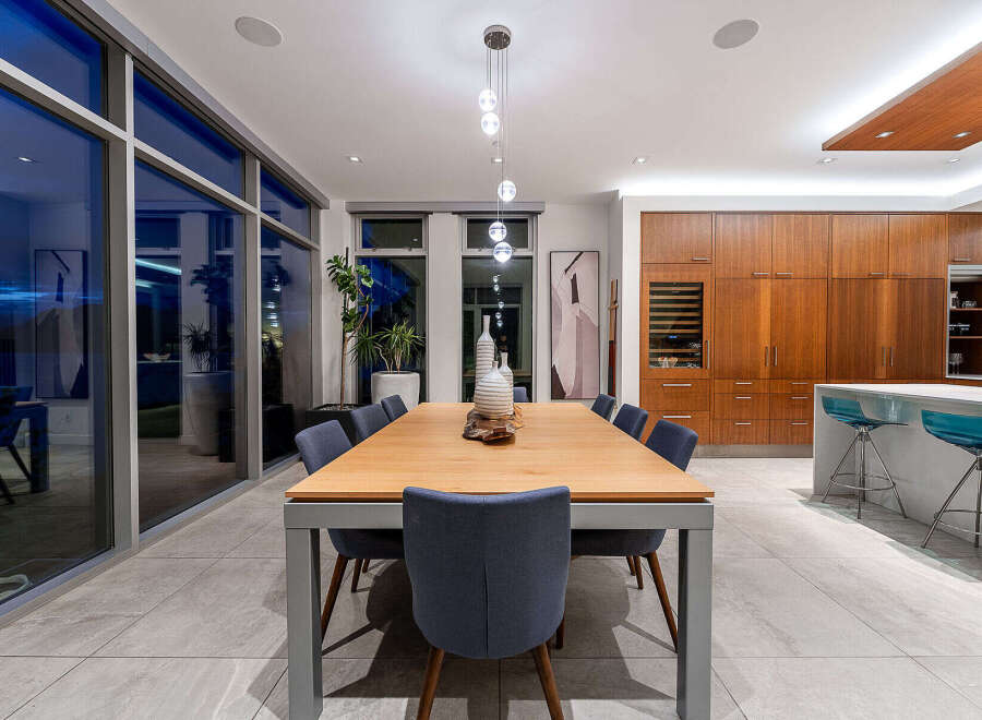 Experience modern luxury in this stunning dining area, featuring a sleek wooden dining table with comfortable upholstered chairs.