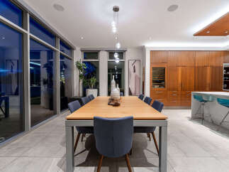 Experience modern luxury in this stunning dining area, featuring a sleek wooden dining table with comfortable upholstered chairs.