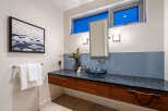 This modern bathroom features a floating vanity with rich wood cabinetry and a sleek granite countertop.