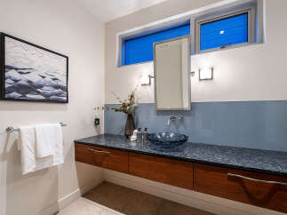 This modern bathroom features a floating vanity with rich wood cabinetry and a sleek granite countertop.