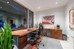 This modern office space features a sleek wooden desk with integrated storage, complemented by an ergonomic chair.