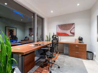 This modern office space features a sleek wooden desk with integrated storage, complemented by an ergonomic chair.