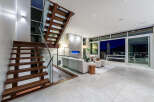 Experience modern luxury in this stunning living space featuring a floating wooden staircase with glass railings.