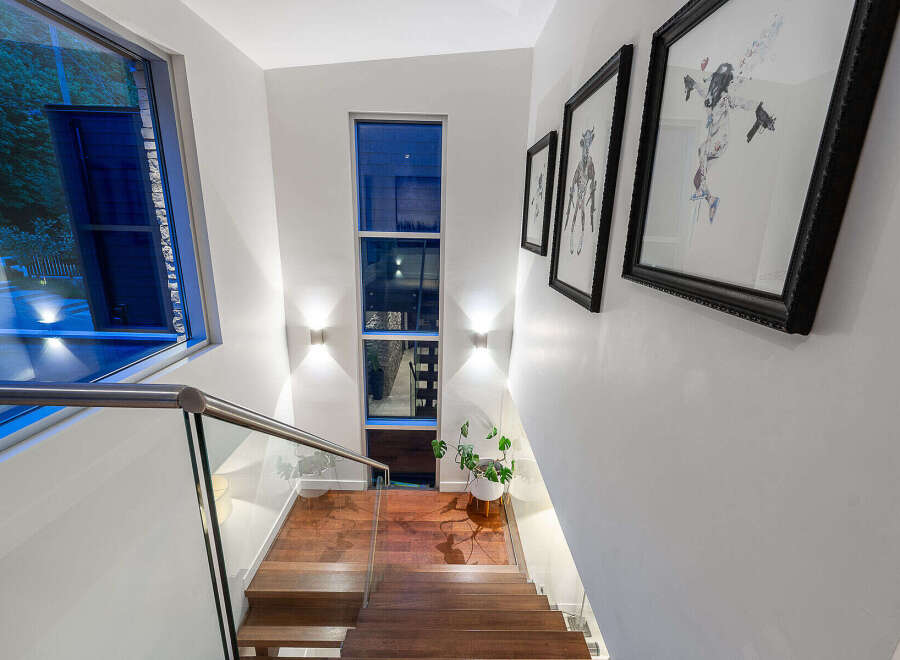 Experience modern living with this stunning staircase featuring a sleek glass railing and rich hardwood treads.