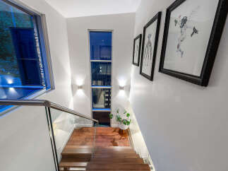 Experience modern living with this stunning staircase featuring a sleek glass railing and rich hardwood treads.