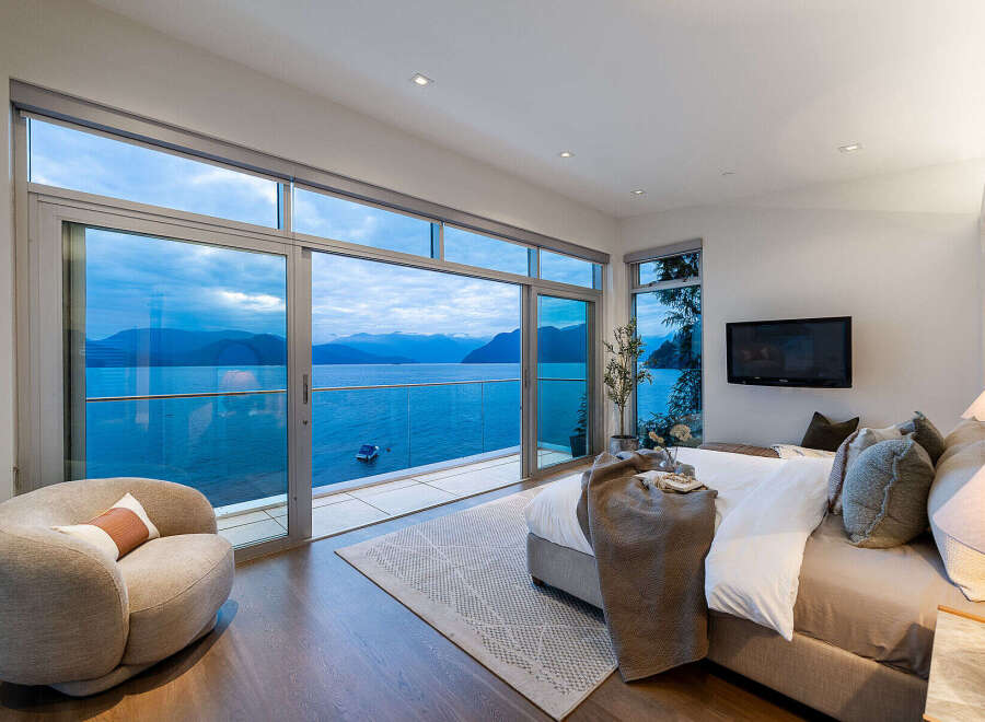 Experience luxury living with this stunning bedroom featuring panoramic ocean views through floor-to-ceiling windows.