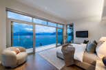 Experience luxury living with this stunning bedroom featuring panoramic ocean views through floor-to-ceiling windows.