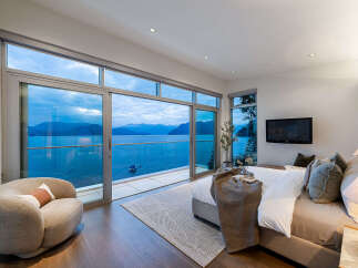 Experience luxury living with this stunning bedroom featuring panoramic ocean views through floor-to-ceiling windows.