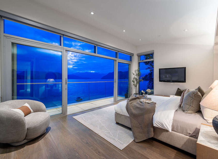 Experience breathtaking ocean views from this luxurious master bedroom, featuring expansive floor-to-ceiling windows that open to a private balcony.