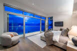 Experience breathtaking ocean views from this luxurious master bedroom, featuring expansive floor-to-ceiling windows that open to a private balcony.