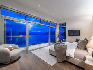 Experience breathtaking ocean views from this luxurious master bedroom, featuring expansive floor-to-ceiling windows that open to a private balcony.