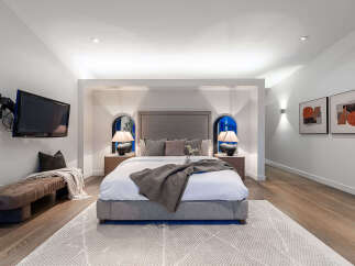 Experience ultimate comfort in this luxurious master bedroom, featuring a king-sized bed with a plush headboard and coordinated throw pillows.