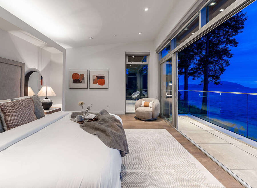Experience breathtaking ocean views from this luxurious master bedroom, featuring a king-sized bed and direct access to a private balcony.