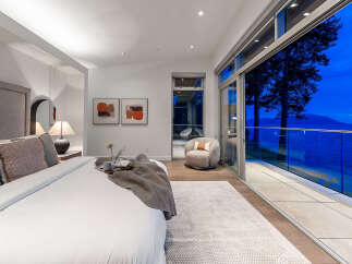 Experience breathtaking ocean views from this luxurious master bedroom, featuring a king-sized bed and direct access to a private balcony.