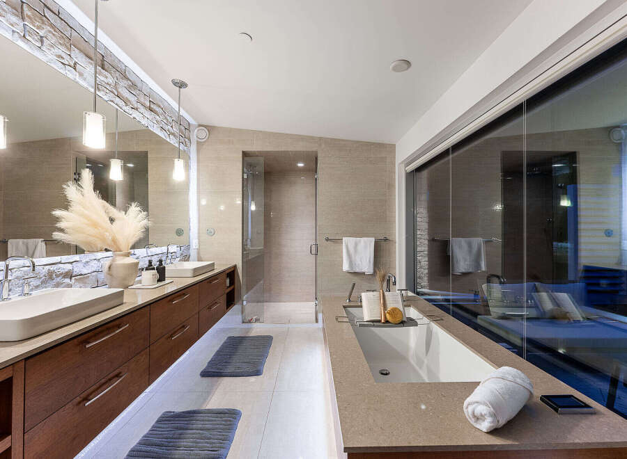 Experience luxury in this modern bathroom featuring dual vessel sinks atop a sleek, floating vanity with ample storage.