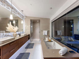 Experience luxury in this modern bathroom featuring dual vessel sinks atop a sleek, floating vanity with ample storage.