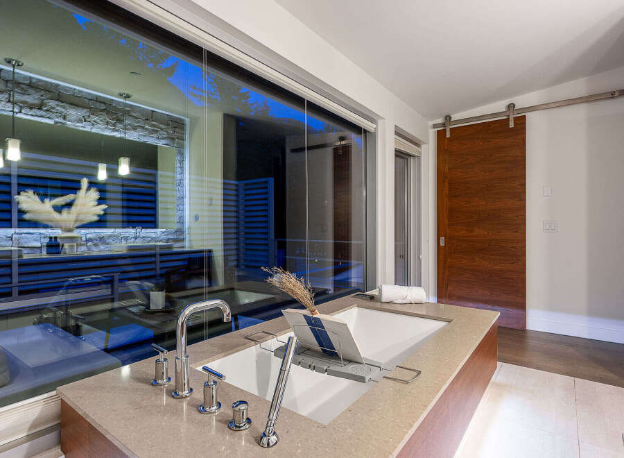 Experience luxury in this modern bathroom featuring a deep soaking tub with a sleek chrome faucet and a convenient bath tray.