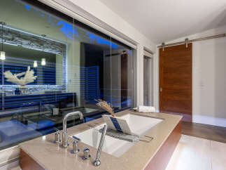 Experience luxury in this modern bathroom featuring a deep soaking tub with a sleek chrome faucet and a convenient bath tray.