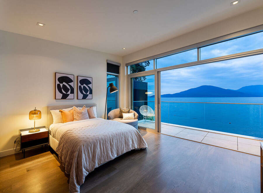 Experience luxurious living with this stunning bedroom featuring a king-sized bed, elegant decor, and breathtaking ocean views.
