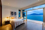 Experience luxurious living with this stunning bedroom featuring a king-sized bed, elegant decor, and breathtaking ocean views.