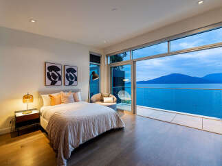 Experience luxurious living with this stunning bedroom featuring a king-sized bed, elegant decor, and breathtaking ocean views.
