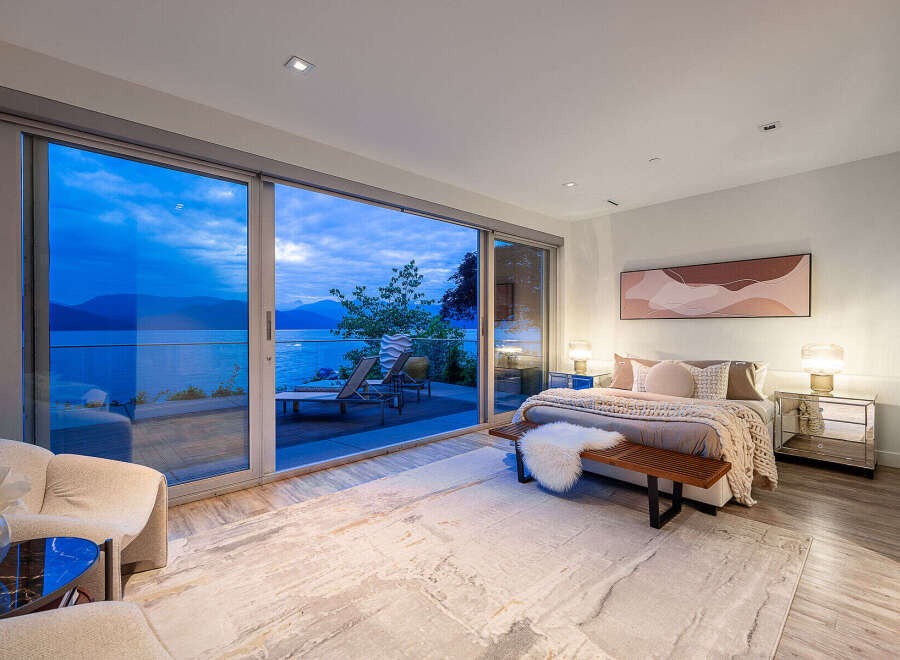 Experience luxurious living with this stunning bedroom featuring expansive sliding glass doors that open to breathtaking ocean and mountain views.