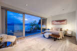 Experience luxurious living with this stunning bedroom featuring expansive sliding glass doors that open to breathtaking ocean and mountain views.