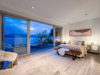Experience luxurious living with this stunning bedroom featuring expansive sliding glass doors that open to breathtaking ocean and mountain views.