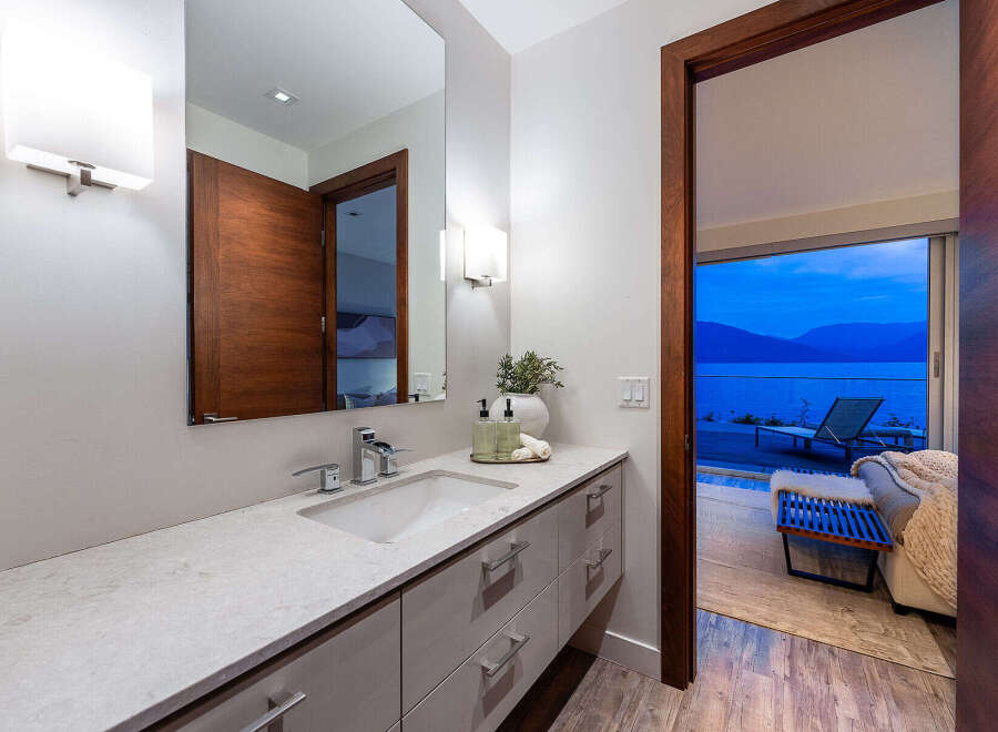 Experience luxury living with this stunning bathroom featuring a sleek vanity, modern fixtures, and a large mirror.