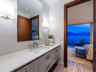 Experience luxury living with this stunning bathroom featuring a sleek vanity, modern fixtures, and a large mirror.