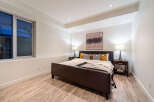 This modern bedroom features a luxurious dark leather bed with a stylish patterned throw and accent pillows.
