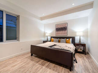 This modern bedroom features a luxurious dark leather bed with a stylish patterned throw and accent pillows.
