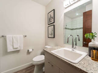 This modern bathroom features a sleek vanity with a granite countertop, complemented by a clean white sink and a contemporary faucet.