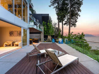 Experience luxury living with this stunning modern home featuring expansive glass doors and windows that seamlessly blend indoor and outdoor spaces.